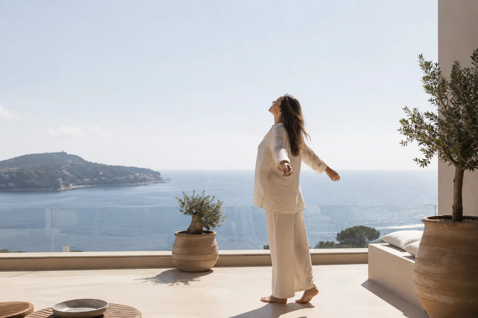 A woman on a sunlit terrace overlooking the Mediterranean coast